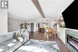 Open-concept living space featuring wood flooring, recessed lighting, and a vaulted ceiling with a decorative beam - 
