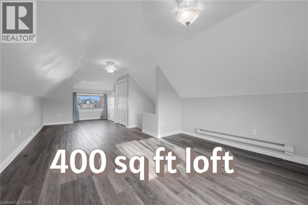 Spacious loft featuring wood-finish flooring, white walls, multiple built-in closets, and two ceiling-mounted light fixtures - 9 Melrose Avenue S Unit# Upper, Hamilton, ON