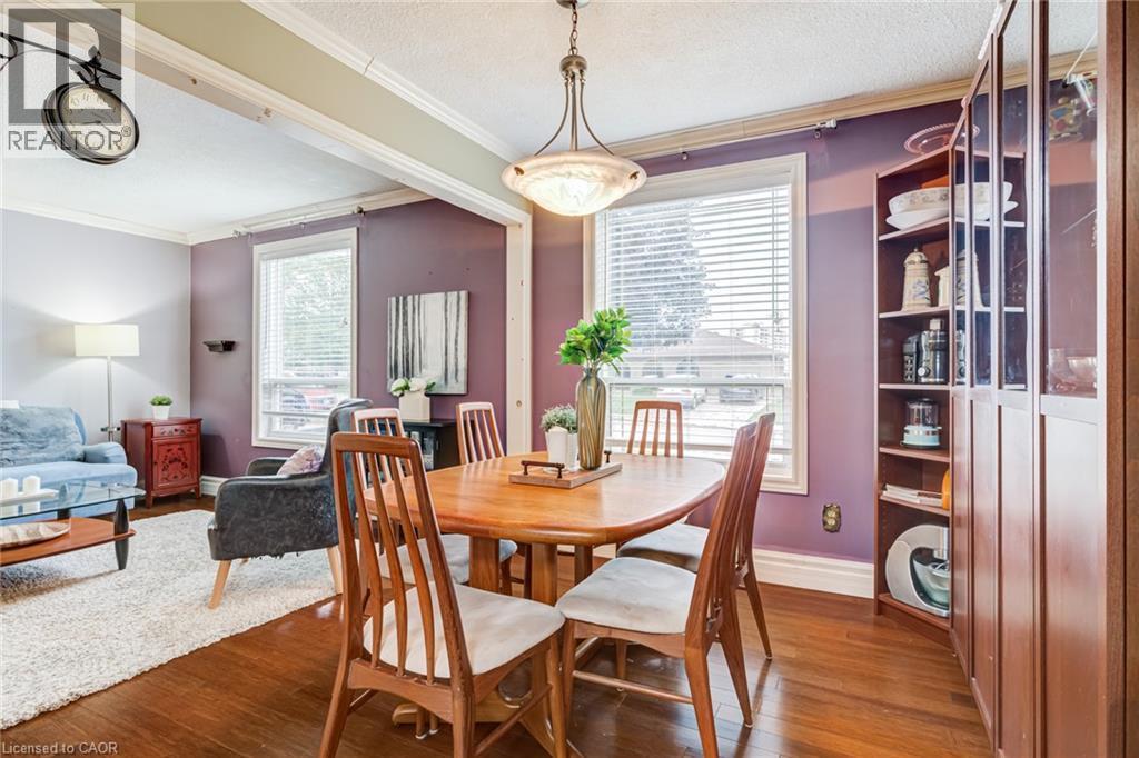 Hardwood-finish flooring, built-in shelving, two large windows with blinds, and ceiling-mounted lighting - 106 Appleford Road, Hamilton, ON