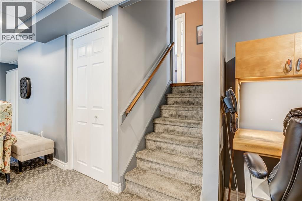 Carpeted stairs with wood handrail, bi-fold door, recessed lighting, and wall-mounted cabinetry - 106 Appleford Road, Hamilton, ON