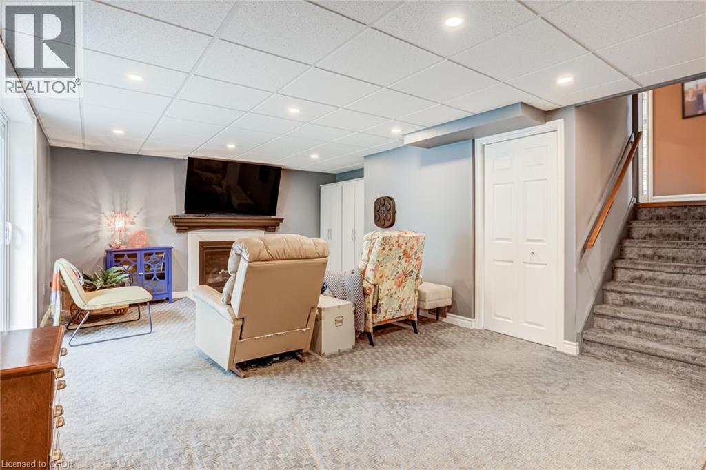Carpeted flooring, recessed lighting, fireplace with wood mantel, built-in bi-fold closet, and a staircase with a wooden handrail - 106 Appleford Road, Hamilton, ON