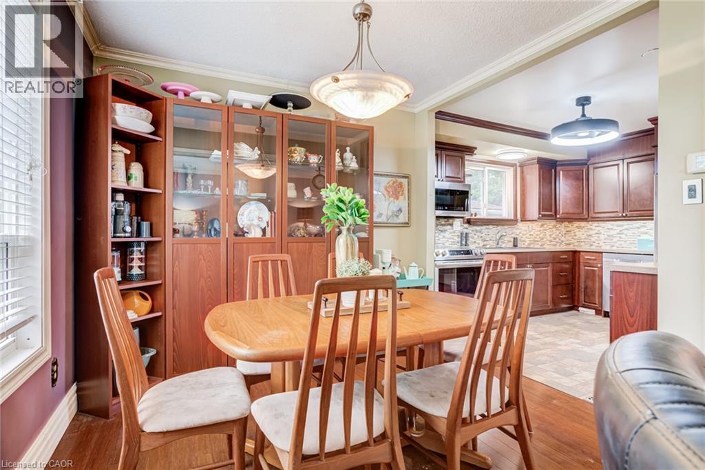 Built-in cabinetry with glass-front display, overhead lighting, wood-finish flooring, and crown molding - 106 Appleford Road, Hamilton, ON