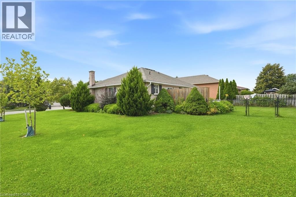 Expansive lawn area with mature landscaping, a privacy fence, and a brick exterior dwelling - 9 Country Club Road, Cayuga, ON