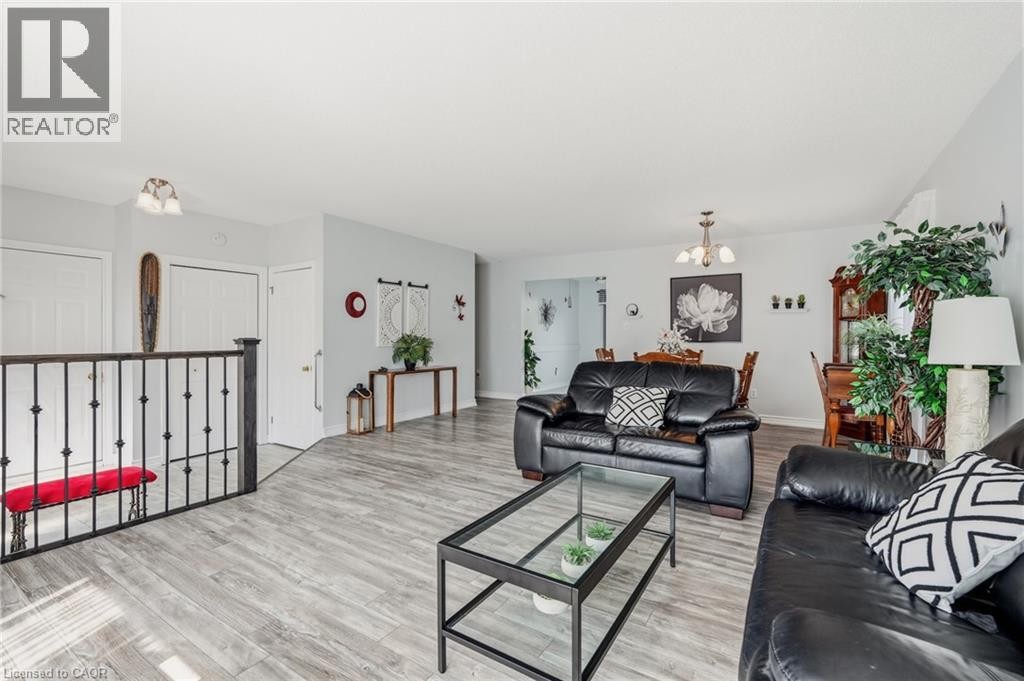 Wood-finish flooring throughout, with a decorative iron railing and white interior doors - 9 Country Club Road, Cayuga, ON