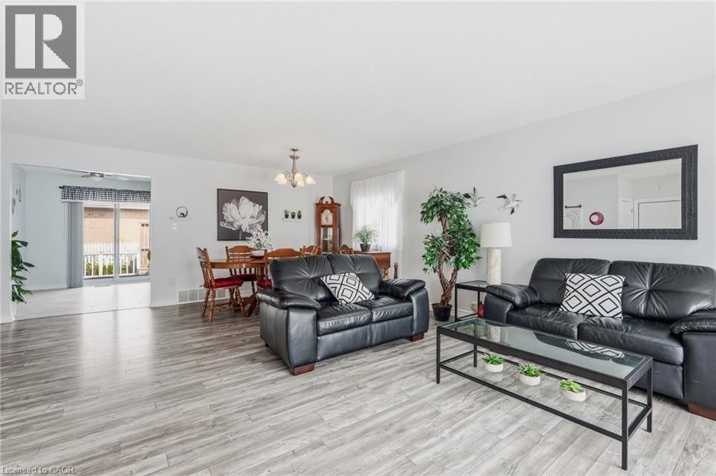 Light wood-finish flooring throughout, bright white walls, and a recessed dining area with a chandelier - 9 Country Club Road, Cayuga, ON
