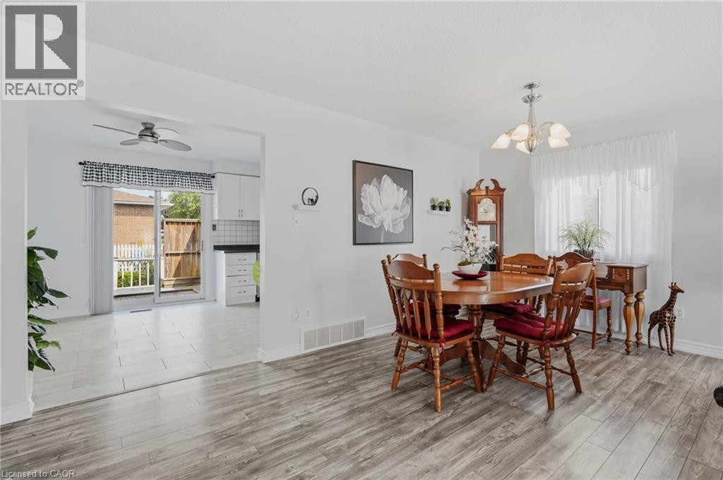 Open concept living area with wood-finish flooring, white walls, and a multi-light chandelier - 9 Country Club Road, Cayuga, ON