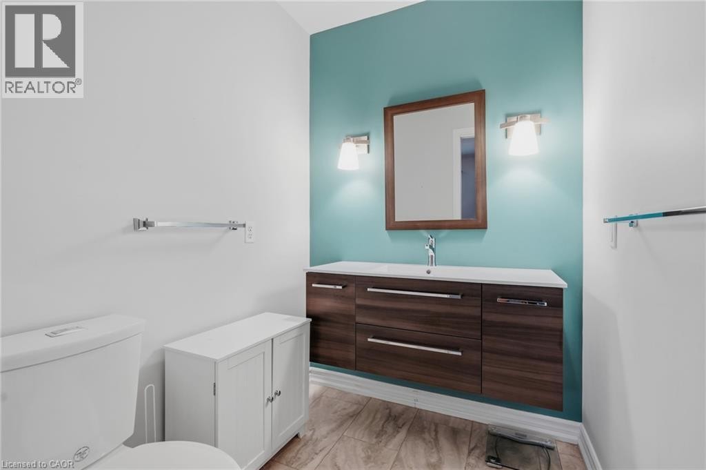 Floating wood-finish vanity with an integrated sink, framed mirror, and dual wall sconces - 9 Country Club Road, Cayuga, ON