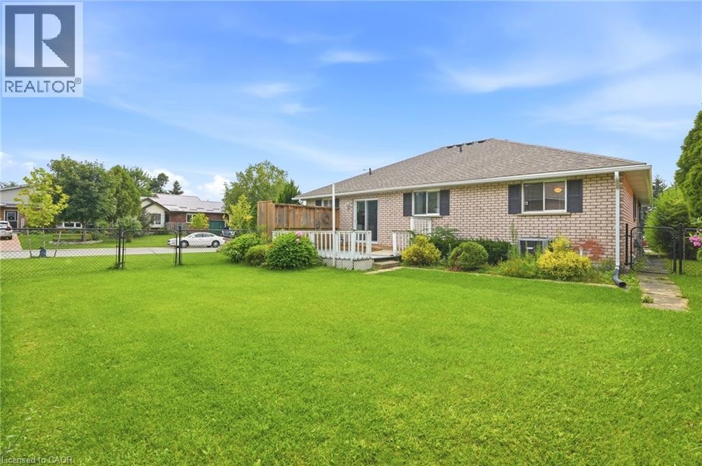 Expansive green lawn, brick exterior, multi-pane windows, and a raised wood-finish deck - 9 Country Club Road, Cayuga, ON