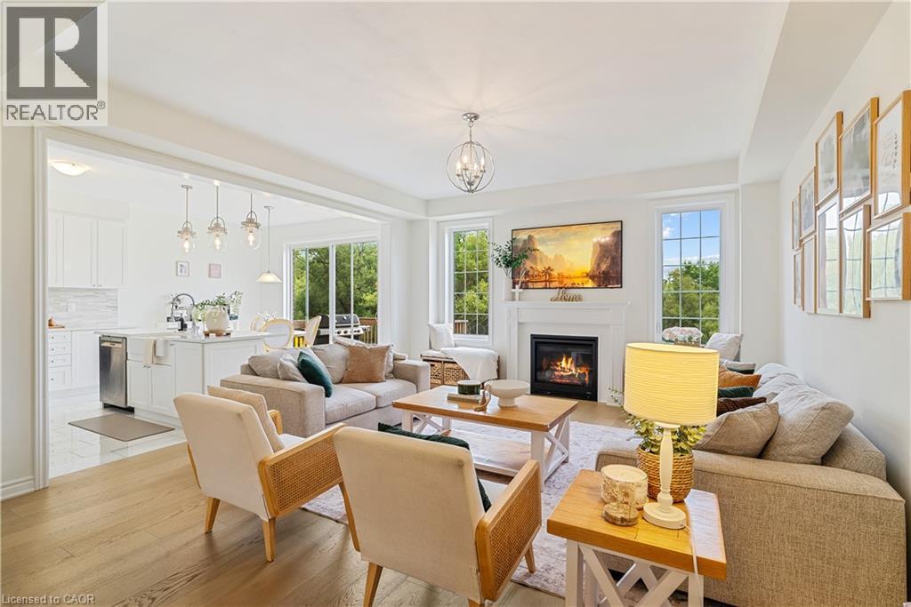 Open-concept living area with wood-finish flooring, a fireplace with mantel, and multiple windows - 68 Barkerville Drive, Whitby, ON