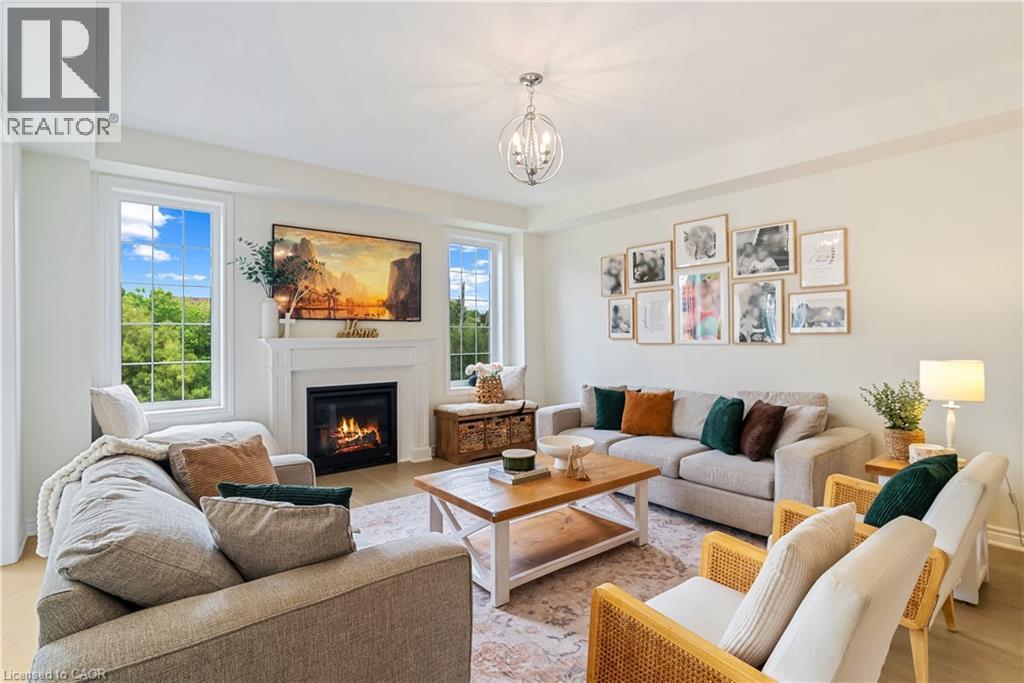 Living area featuring a fireplace with a white mantel, wood-finish flooring, and multiple windows - 68 Barkerville Drive, Whitby, ON