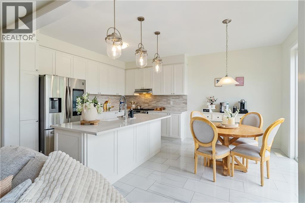 Open-concept kitchen featuring white cabinetry, stainless steel appliances, a central island with a sink, and pendant lighting - 68 Barkerville Drive, Whitby, ON
