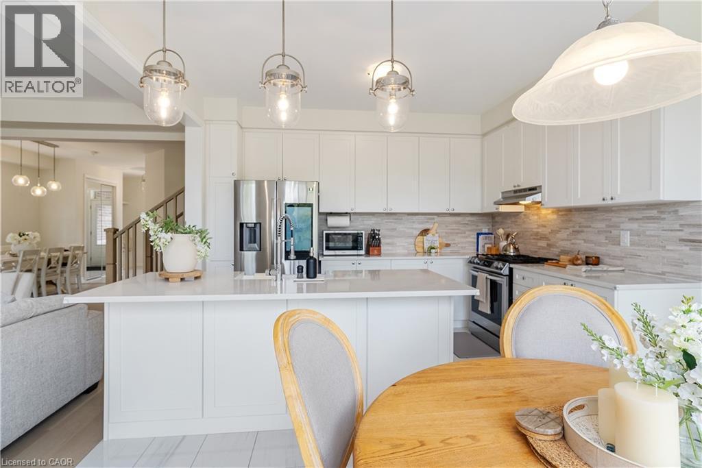 White cabinetry, stainless steel appliances, pendant lighting, light-toned countertops, and a tile backsplash - 68 Barkerville Drive, Whitby, ON