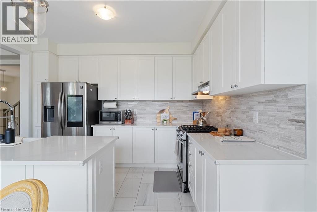 White cabinetry, light countertops, mosaic tile backsplash, stainless steel appliances, and tile flooring - 68 Barkerville Drive, Whitby, ON