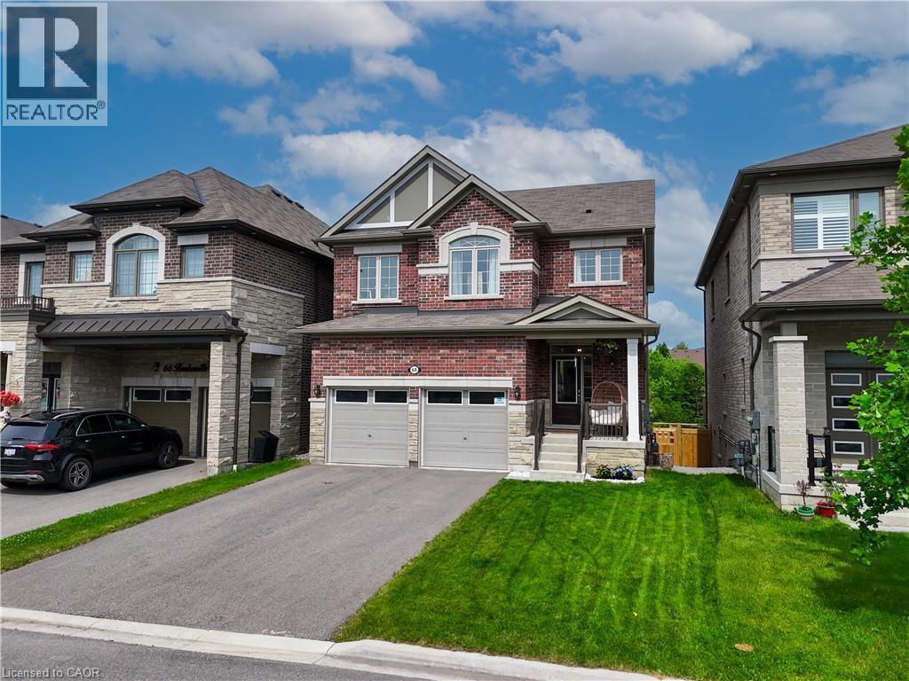 Brick and stone exterior with a covered porch entry, dual garage doors, and a paved driveway - 68 Barkerville Drive, Whitby, ON