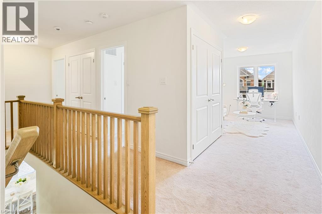Upper-level landing with light wood railing, neutral carpeting, and white walls - 68 Barkerville Drive, Whitby, ON