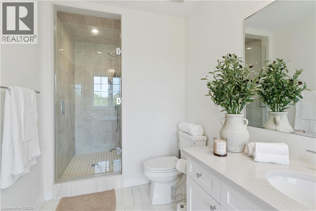 Glass-enclosed shower with tile surround, white vanity with integrated sink, polished chrome fixtures, and a large wall-mounted mirror - 68 Barkerville Drive, Whitby, ON