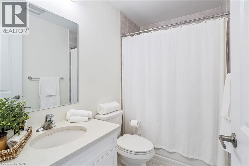 Vanity with integrated sink, rectangular mirror, chrome faucet, and tiled shower surround - 68 Barkerville Drive, Whitby, ON