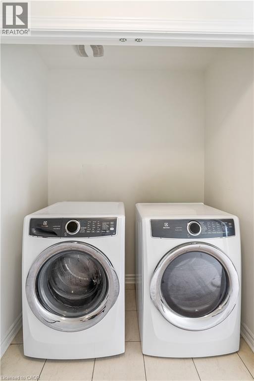 Built-in laundry nook with light-toned tiled flooring - 68 Barkerville Drive, Whitby, ON