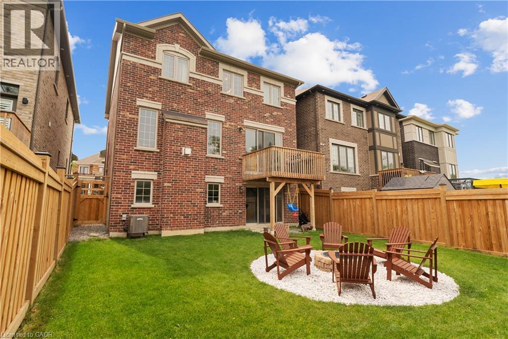 Brick exterior with multiple windows, elevated wood deck, lower-level sliding glass door, and a private fenced yard - 68 Barkerville Drive, Whitby, ON