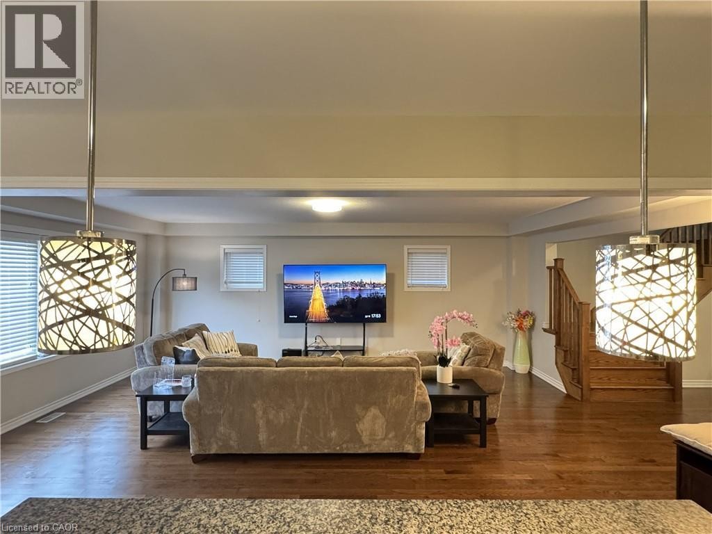 Open living area featuring wood-finish flooring, recessed lighting, and decorative pendant light fixtures - 67 Pointer Street, Cambridge, ON