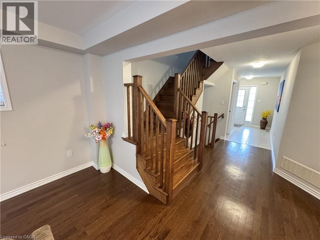 Hardwood flooring throughout, a two-story staircase with wood banister, and a front entry with tile flooring and a glass-paneled door - 67 Pointer Street, Cambridge, ON