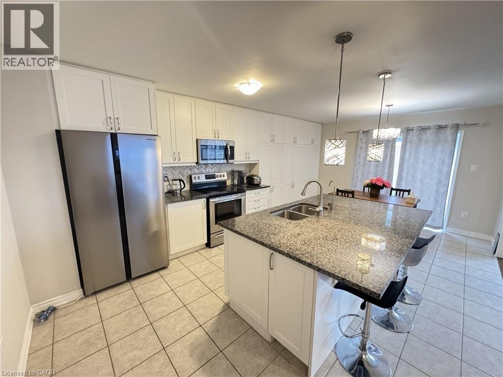 Kitchen featuring an island with a dual basin sink, granite countertop, and pendant lighting - 67 Pointer Street, Cambridge, ON
