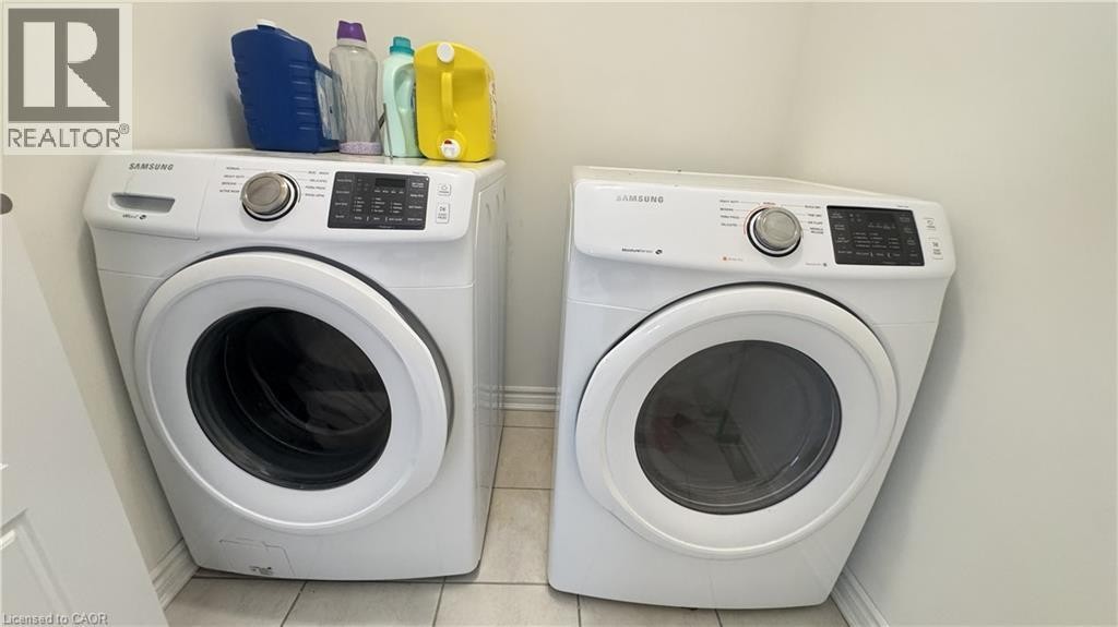 Laundry area with a built-in front-load washer and dryer set, featuring a tiled floor - 67 Pointer Street, Cambridge, ON