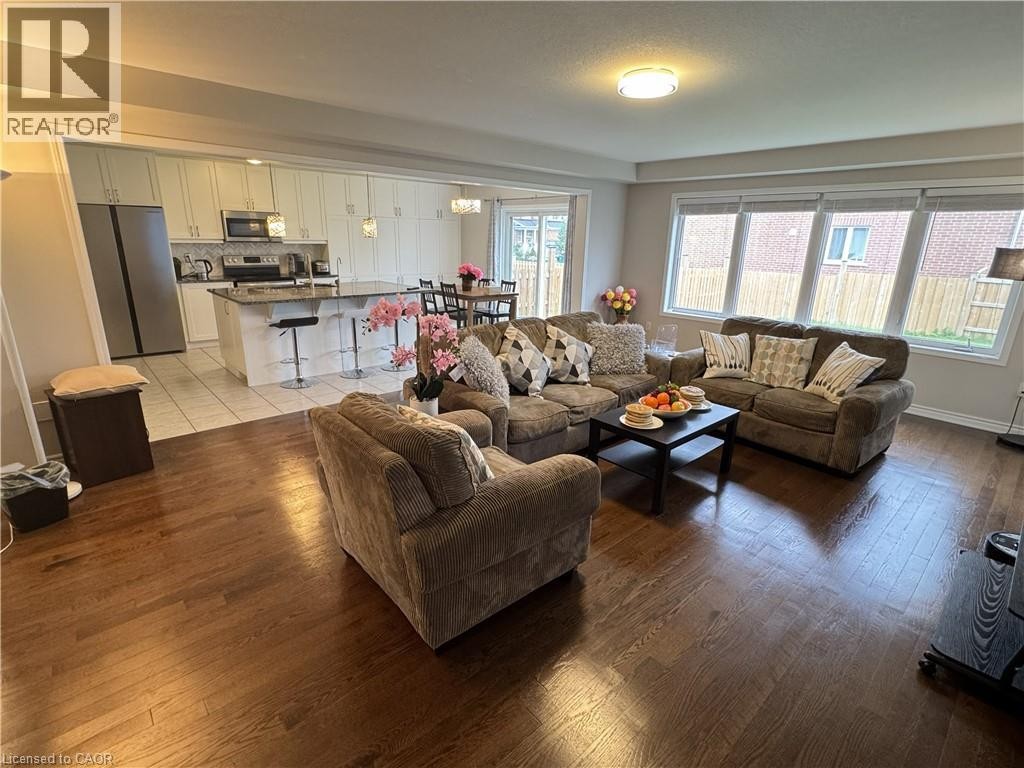 Open-concept living space featuring wood-finish flooring, a kitchen with stainless steel appliances, a center island with bar seating, and recessed lighting - 67 Pointer Street, Cambridge, ON