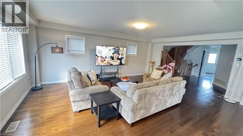 Wood-finish flooring throughout, multiple windows with blinds, and an open entryway to a wooden staircase with balusters - 67 Pointer Street, Cambridge, ON 