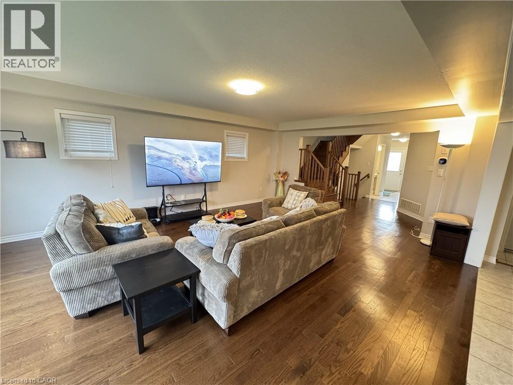 Spacious living area featuring wood-finish flooring, recessed lighting, and multiple windows with blinds - 67 Pointer Street, Cambridge, ON