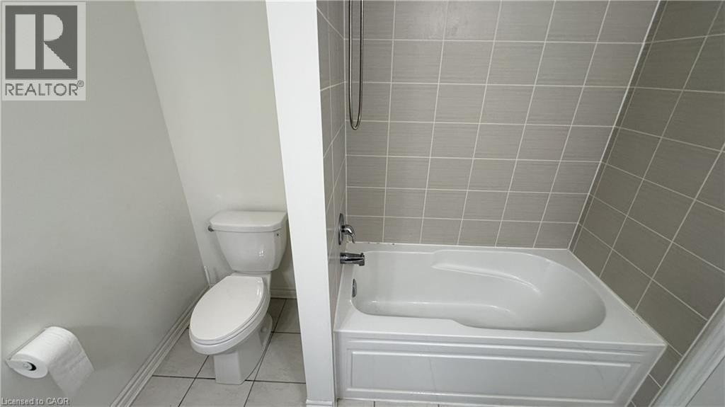 Tiled tub and shower combination with a white porcelain toilet - 67 Pointer Street, Cambridge, ON