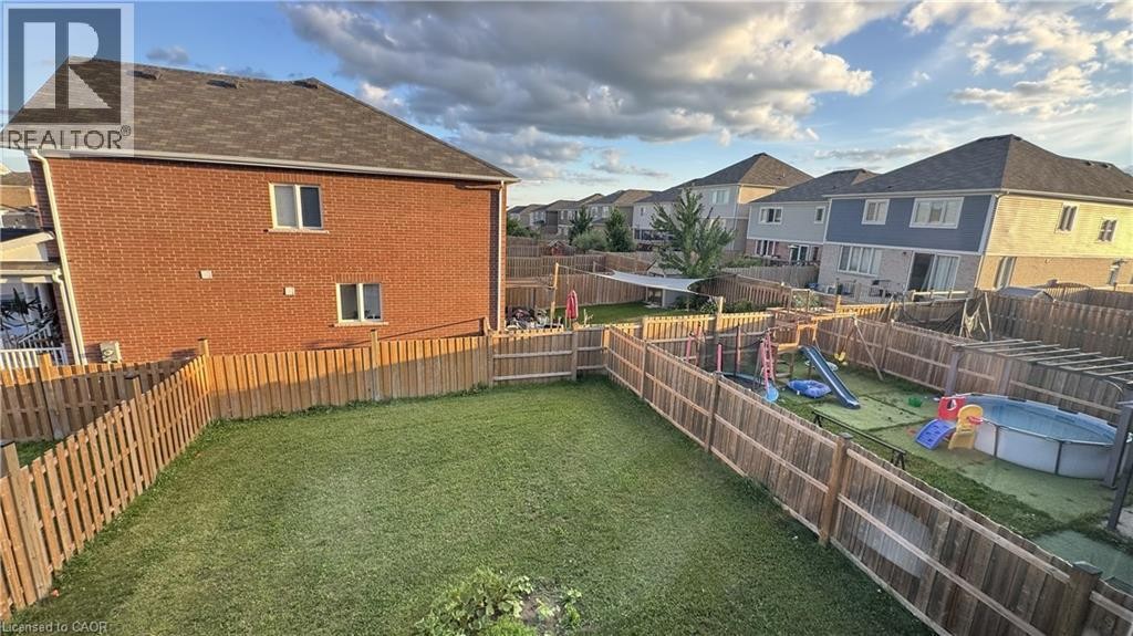 Expansive backyard featuring a manicured lawn, wood fencing, and a brick exterior - 67 Pointer Street, Cambridge, ON