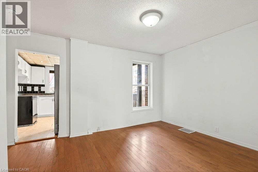Hardwood flooring, white walls, and a window with natural light - 23 Frederick Avenue, Hamilton, ON