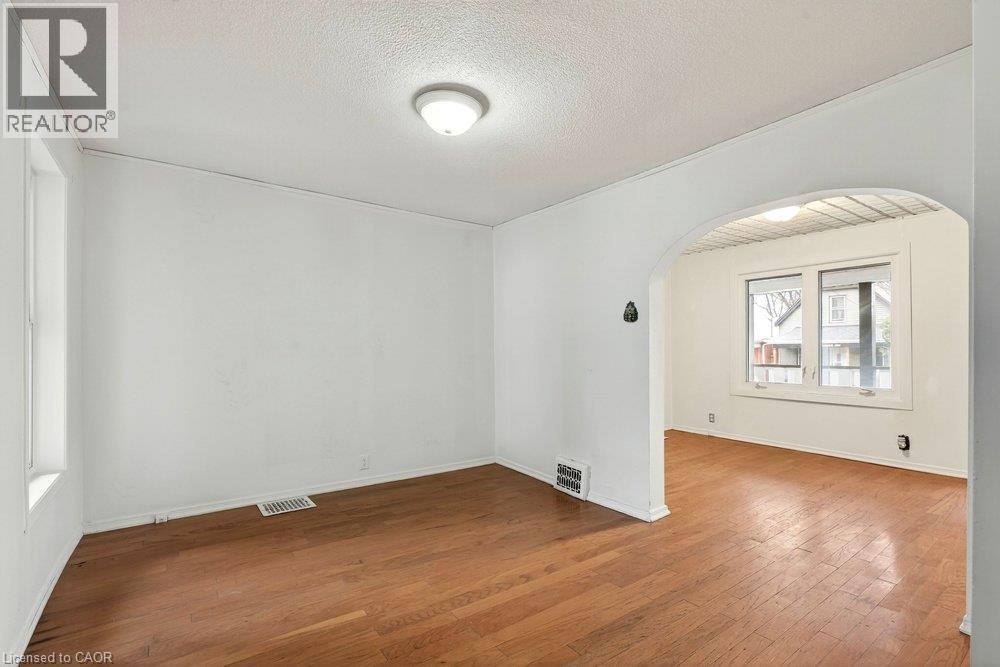 Hardwood flooring, arched doorway, recessed wall heater, and ceiling-mounted light fixtures - 23 Frederick Avenue, Hamilton, ON