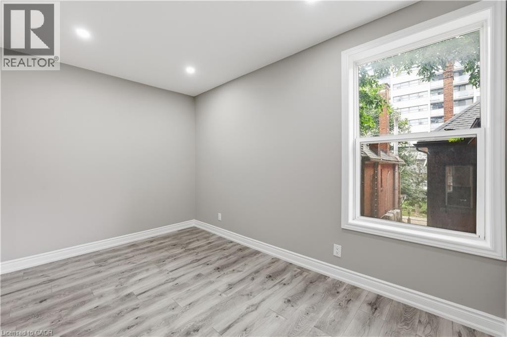 Recessed lighting illuminates neutral-toned walls, enhancing the wood-finish flooring - 98 Duke Street Unit# 2Nd, Hamilton, ON