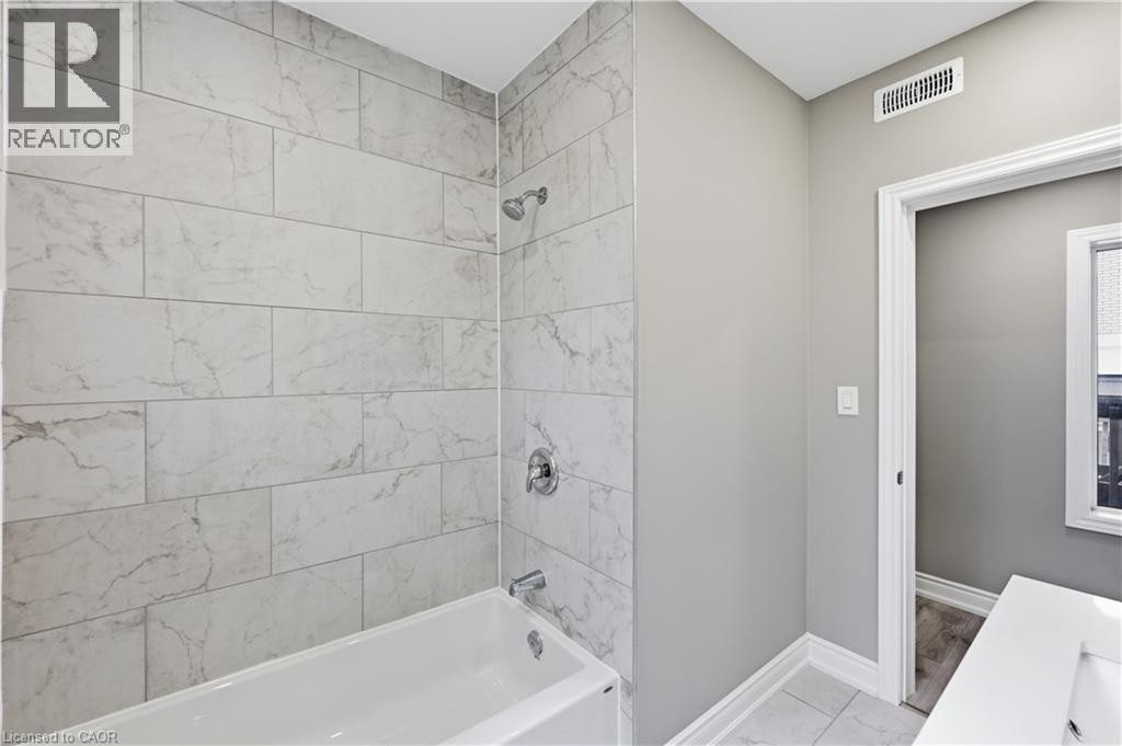 Bathtub with polished chrome fixtures, subway tile surround, and light gray wall paint - 98 Duke Street Unit# 2Nd, Hamilton, ON