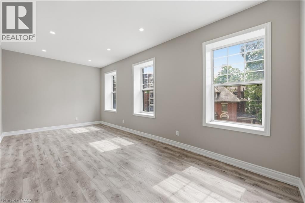 Spacious room featuring wood-finish flooring, recessed lighting, and multiple windows with white trim - 98 Duke Street Unit# 2Nd, Hamilton, ON