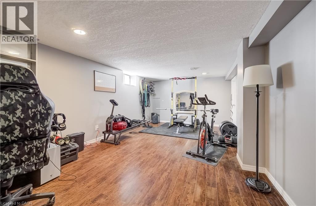 Spacious room with wood-finish flooring, recessed lighting, neutral wall paint, and a built-in shelving unit - 176 Edwin Street, Kitchener, ON