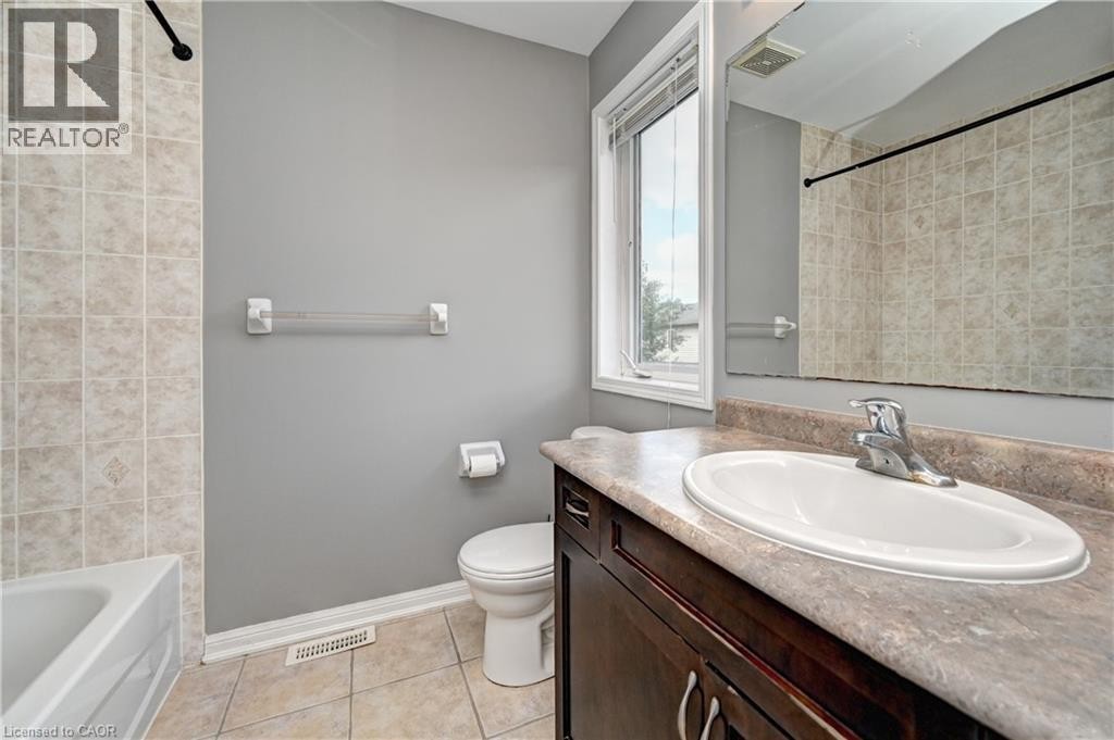 Tile flooring, built-in vanity with laminate countertop, integrated sink with chrome faucet, tiled shower surround, and a window providing natural light - 103 Blackbird Circle, Cambridge, ON