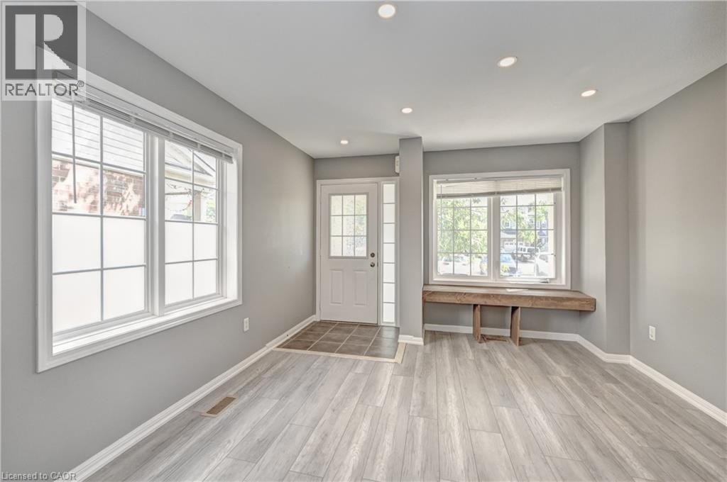 Recessed ceiling lighting, multiple large windows, wood-finish flooring, a glass-paneled entry door, and a built-in window bench - 103 Blackbird Circle, Cambridge, ON
