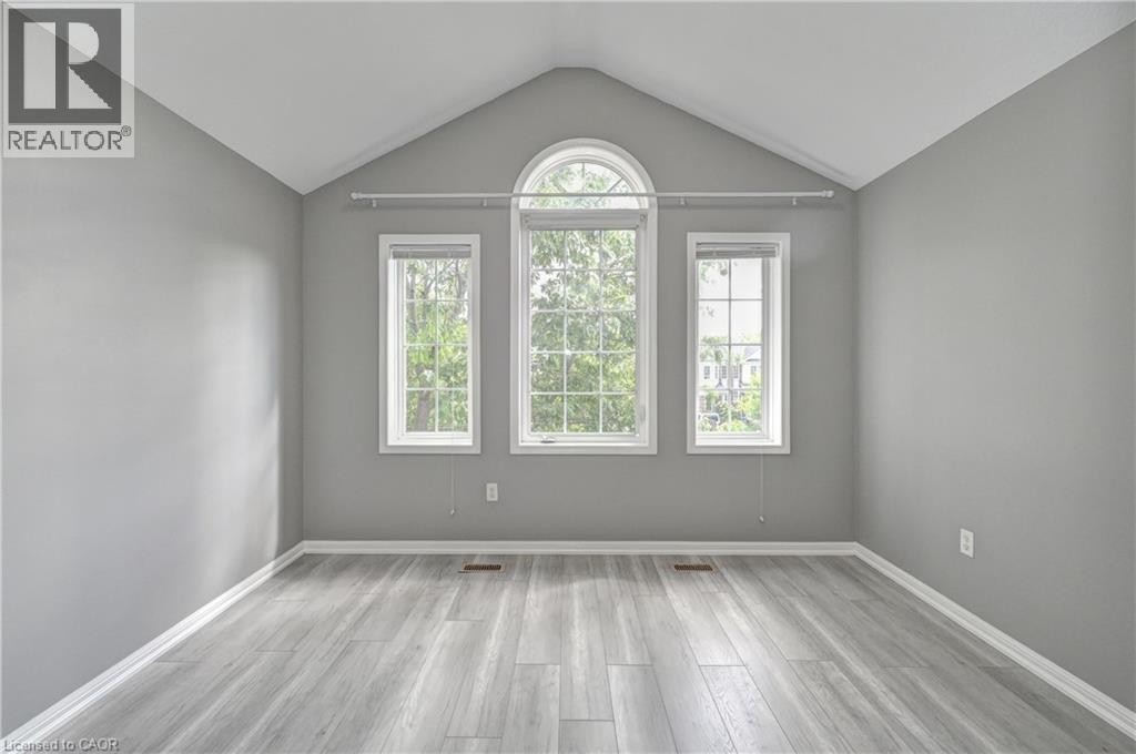 Vaulted ceiling, arched window, two vertical windows, light gray walls, and wood-finish flooring - 103 Blackbird Circle, Cambridge, ON