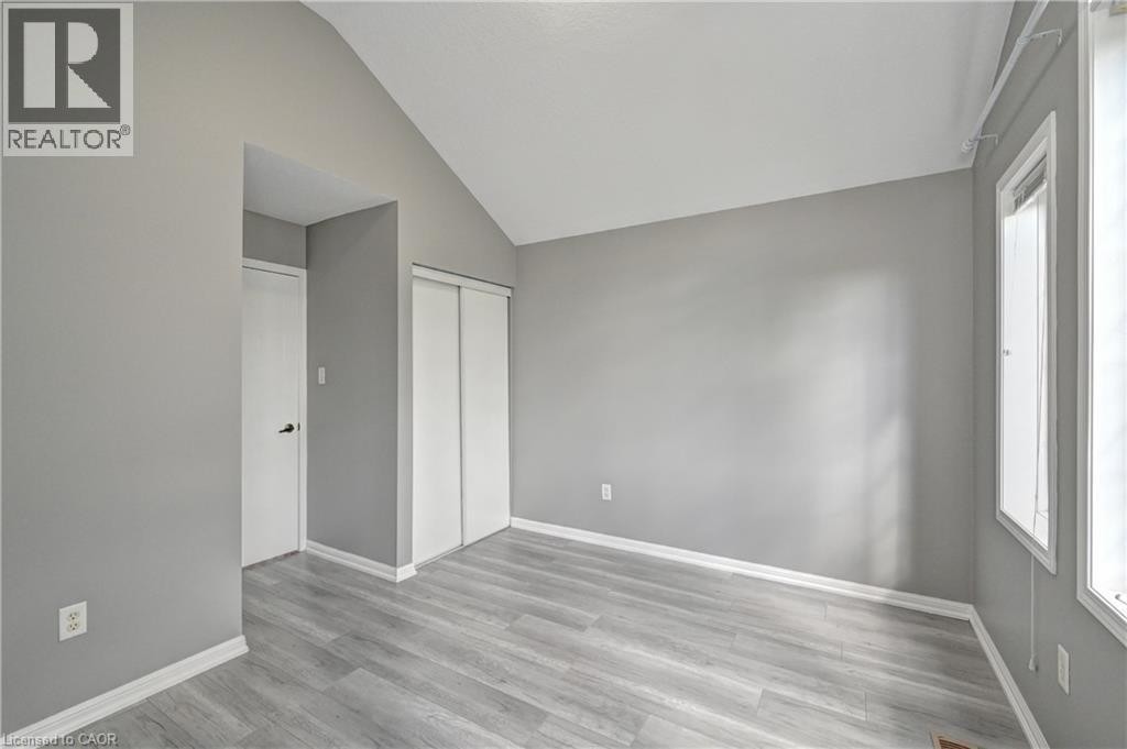 Vaulted ceiling, light wood-finish flooring, white trim, sliding closet doors, and multiple windows - 103 Blackbird Circle, Cambridge, ON
