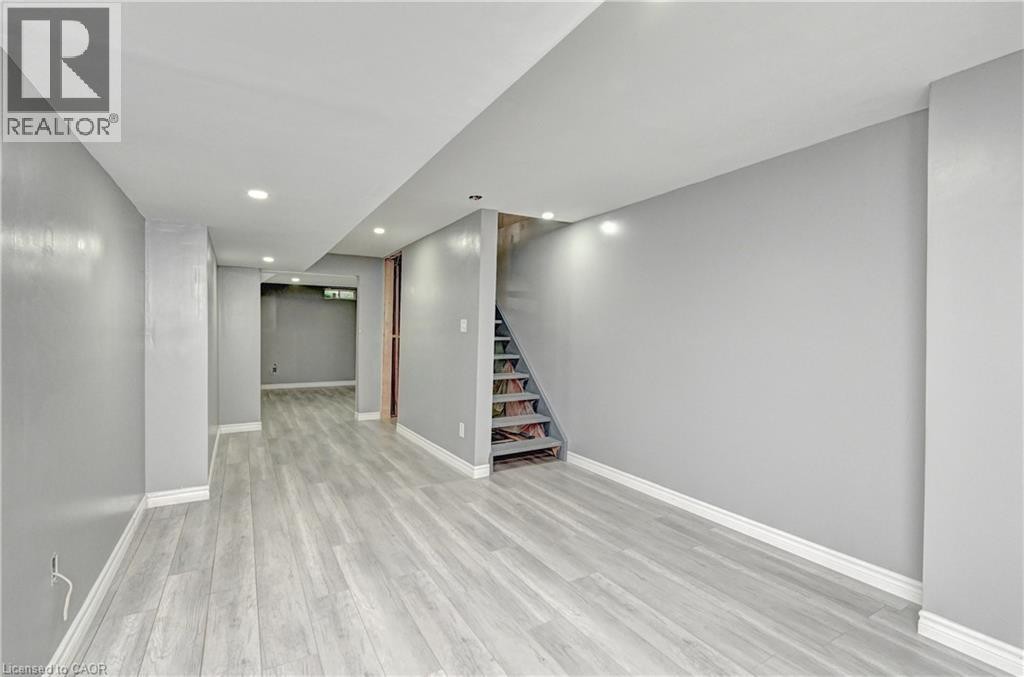 Recessed lighting, wood-finish flooring, light gray wall color, white trim, exposed wooden staircase - 103 Blackbird Circle, Cambridge, ON