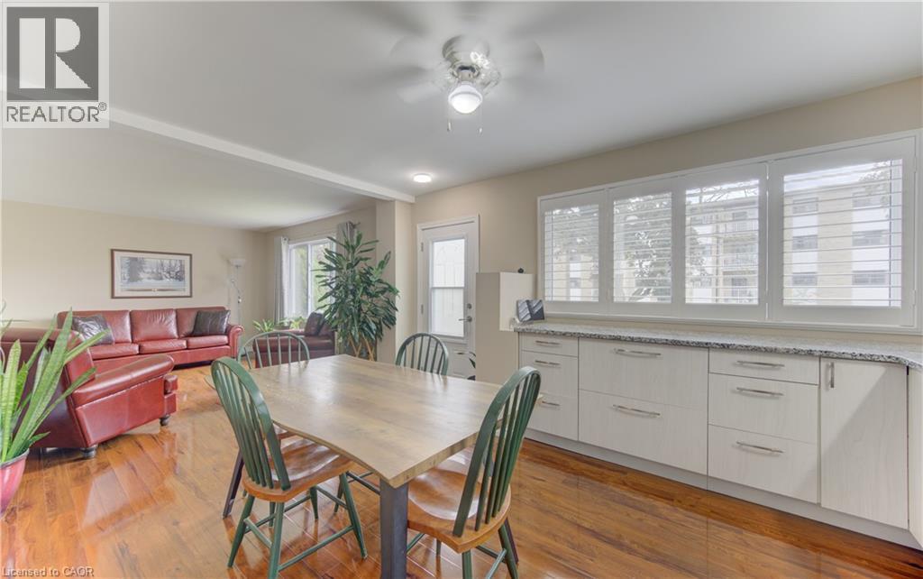 Open-concept living area featuring wood-finish flooring, a ceiling fan with integrated lighting, and extensive cabinetry with a light-toned countertop - 104 Mausser Avenue, Kitchener, ON