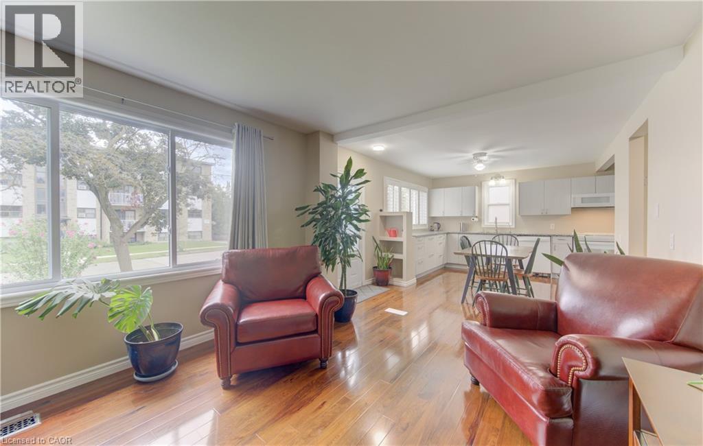 Expansive front windows, wood-finish flooring, white kitchen cabinetry, recessed lighting, and a ceiling-mounted light fixture - 104 Mausser Avenue, Kitchener, ON
