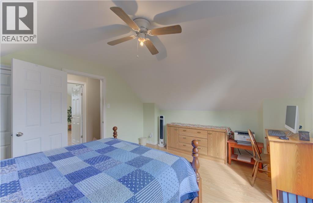 Angled ceiling architecture, light-colored walls, wood-finish flooring, ceiling fan with integrated lighting, and white paneled doors - 104 Mausser Avenue, Kitchener, ON
