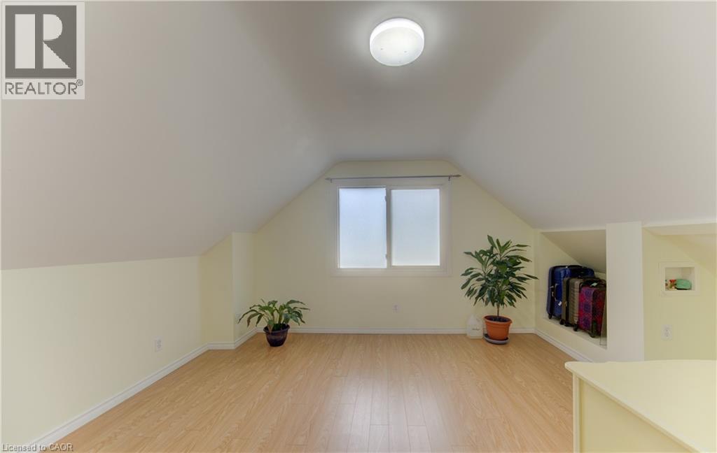 Attic space featuring sloped ceilings, wood-finish flooring, a flush-mount ceiling light, and a built-in storage alcove - 104 Mausser Avenue, Kitchener, ON