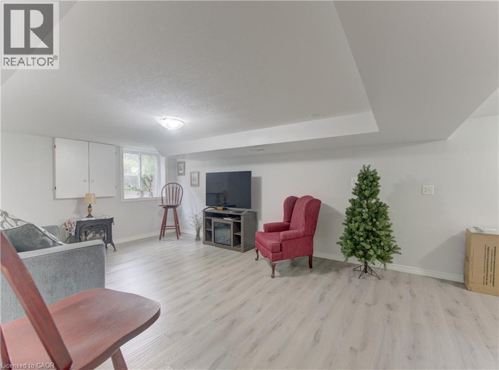 Spacious room with light-toned wood-finish flooring, white walls, and a dropped ceiling feature - 104 Mausser Avenue, Kitchener, ON