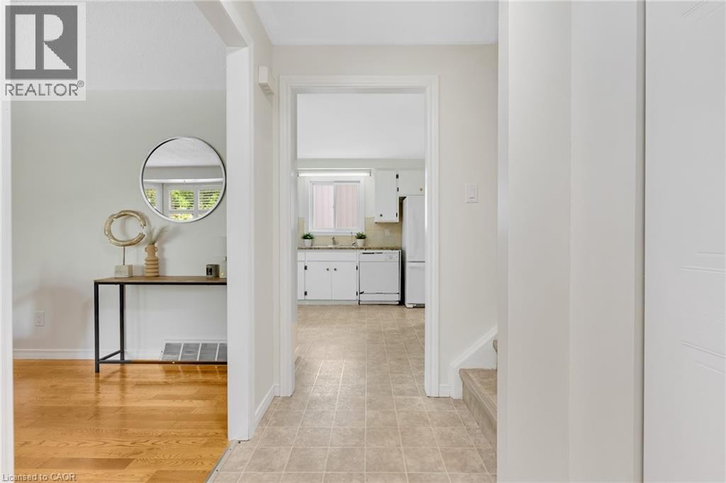 Hardwood flooring, light-colored walls, white kitchen cabinetry, stainless steel sink, and a kitchen window - 7 Underhill Crescent, Kitchener, ON