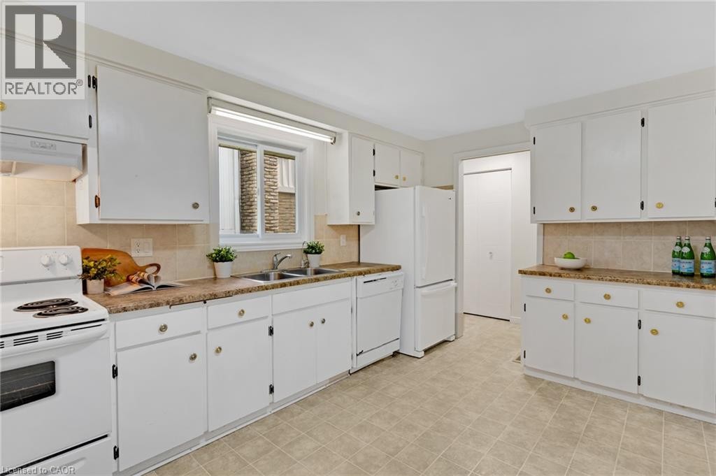 White cabinetry, light-toned tiled flooring, white built-in appliances, and a window above the sink - 7 Underhill Crescent, Kitchener, ON
